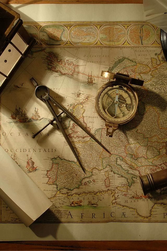 An antique map of Europe with a brass compass and a pair of dividers lying on it.
